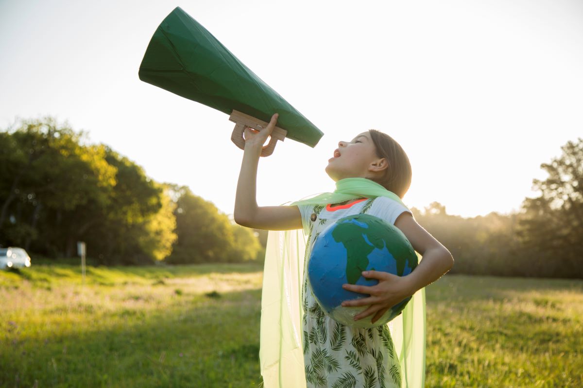 une enfant portant un globe dans ses bras et criant avec un porte-voix