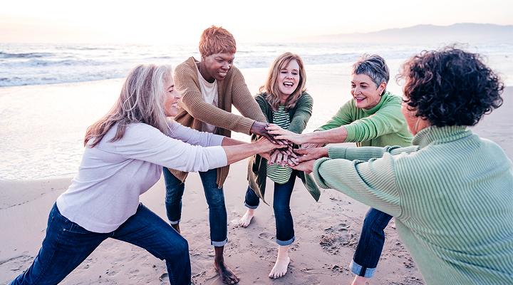 Un groupe de personnes souriantes se tenant par les mains sur la plage.
