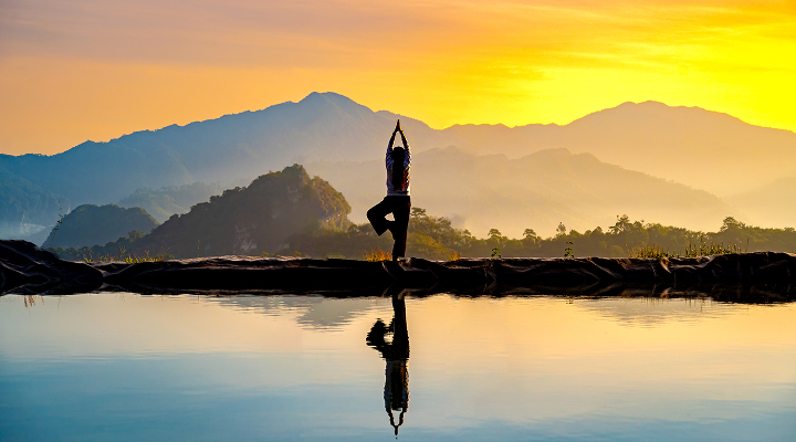 Femme faisant du yoga devant un paysage de montagnes.