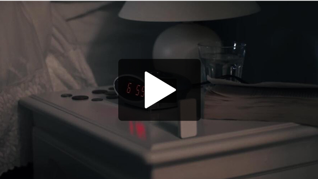 Image fixe tirée d'une vidéo : un réveil numérique sur une table de chevet.